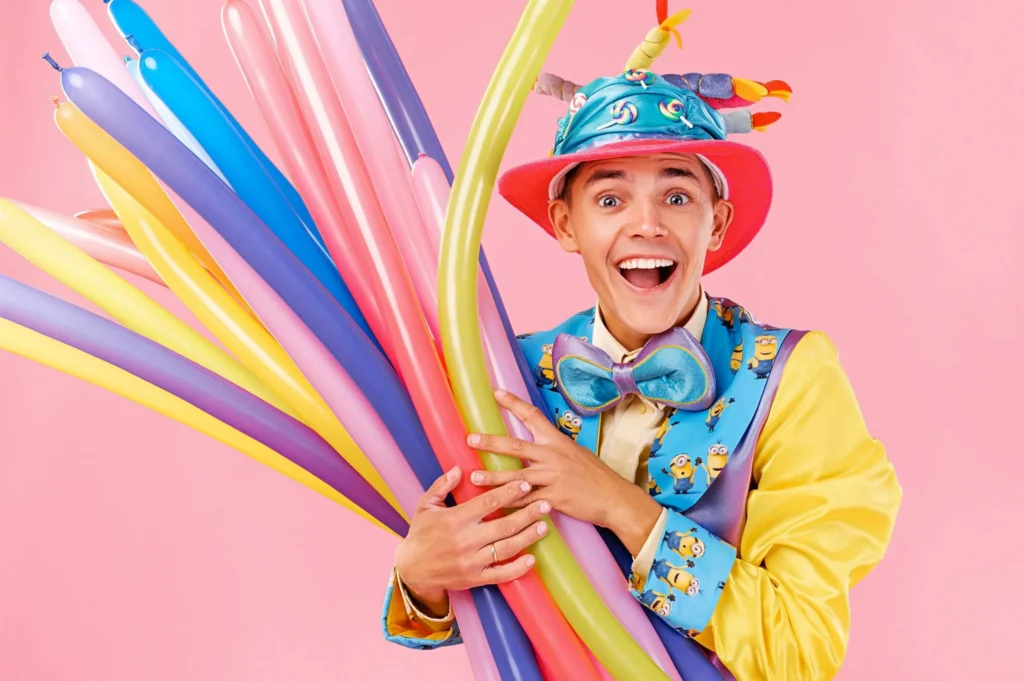 A balloon artist twisting balloon animals surrounded by balloons