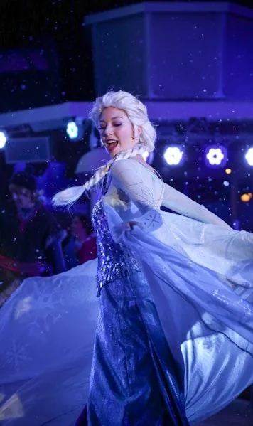 A performer in a winter gown surrounded by falling snow